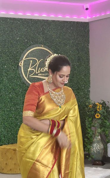 A client in a gold sari in front of the Blush Beauty Bar sign at the salon