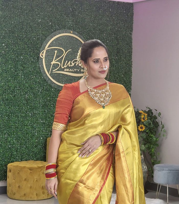 A client in a gold sari in front of the Blush Beauty Bar sign at the salon