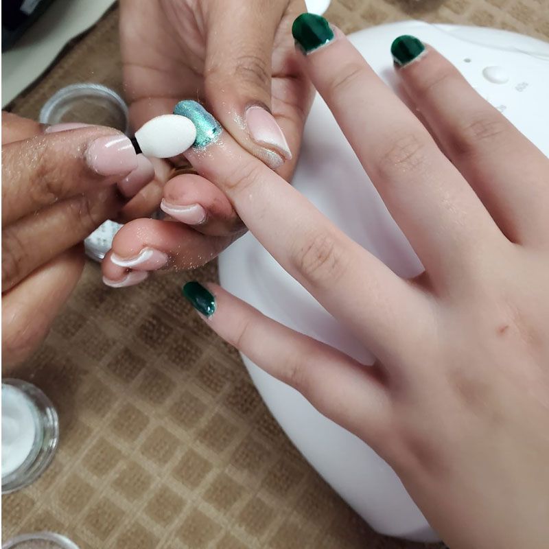 A manicure being finished with green polish