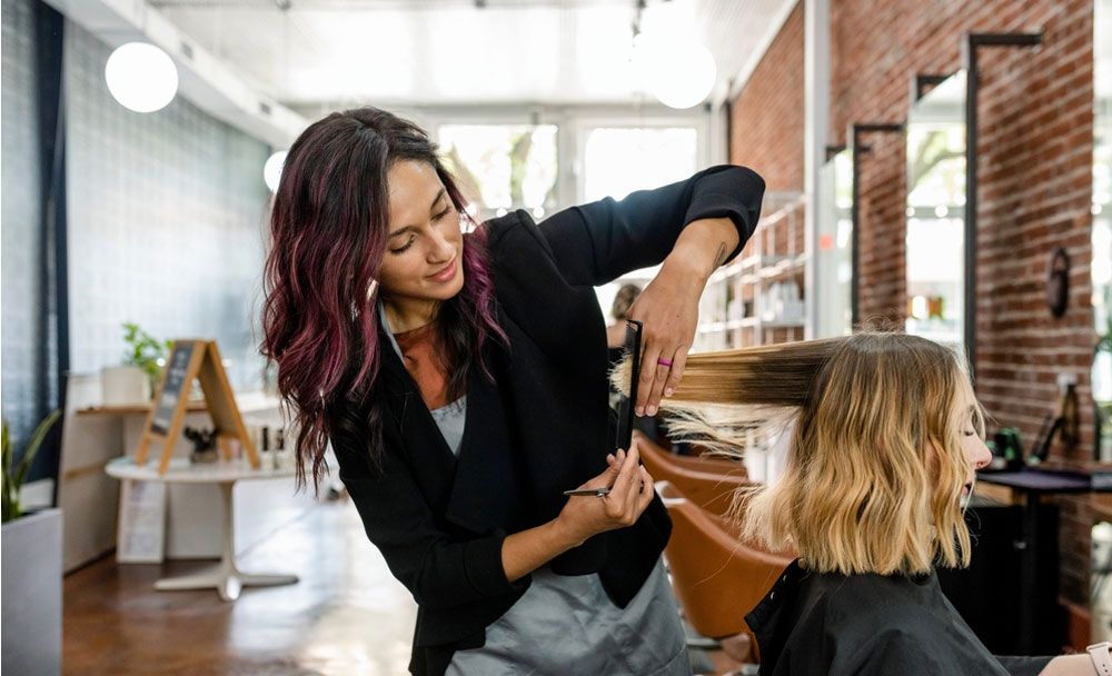 A stylist blow drying a client's hair in a salon